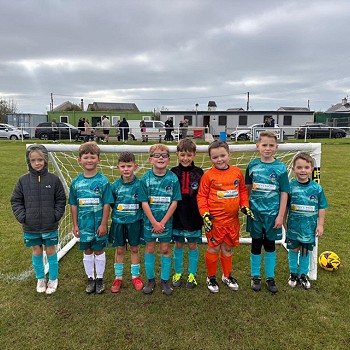 aelodau'r tîm pêl-droed yn sefyll mewn llinell ar y cae