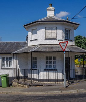 Adeilad gwyn ar gornel stryd